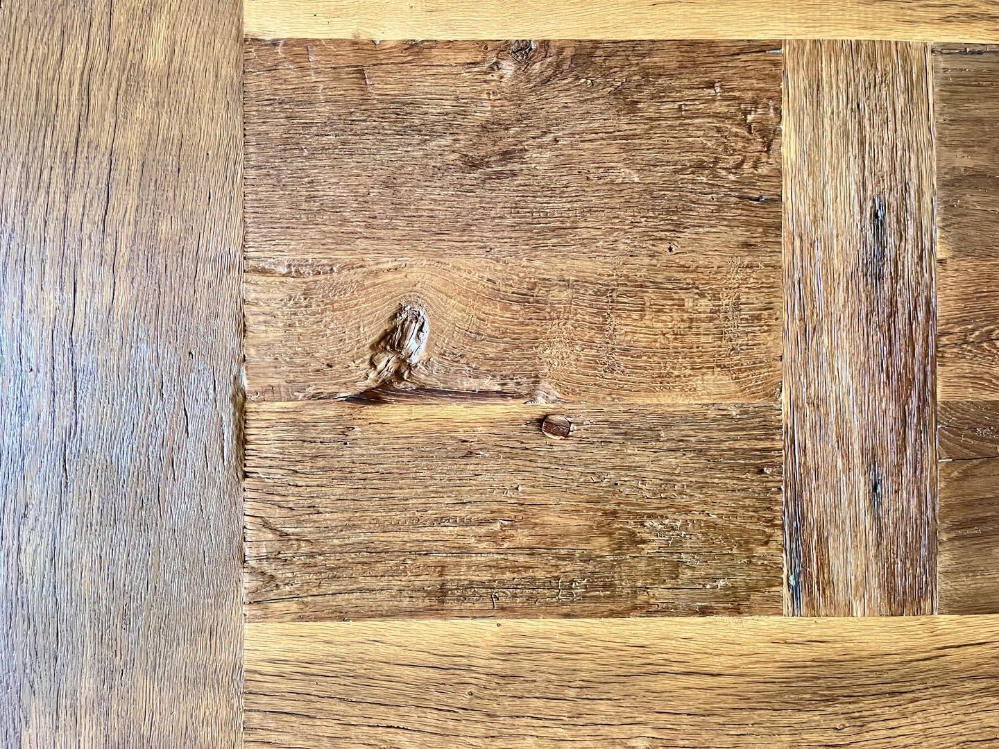 Gros plan sur le centre du plateau en chêne massif ancien de la table Tower, nœuds et veinage prononcés.