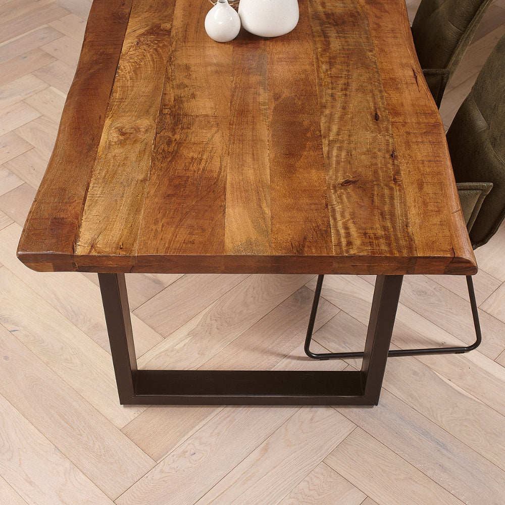 Table en manguier massif avec bords naturels et piétement en métal noir mat en forme de U.
