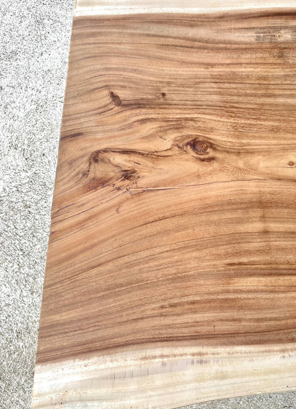 Table en bois de suar massif exotique avec bords naturels préservés et veinage contrasté.